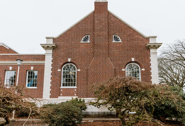 Red brick building with arched windows featuring WindowSLIP installed, white trim detailing, and a central chimney.