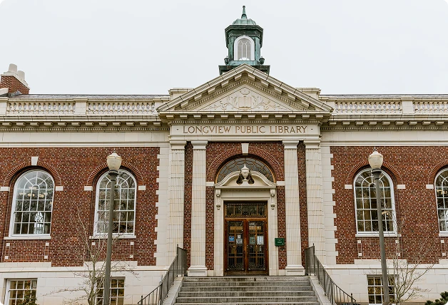 Front view of Longview Public Library with WindowSLIP installed on white-framed arched windows, featuring a red brick exterior and central staircase.