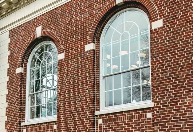 Two large, arched single-pane windows in a red brick building, suggesting potential draft issues.